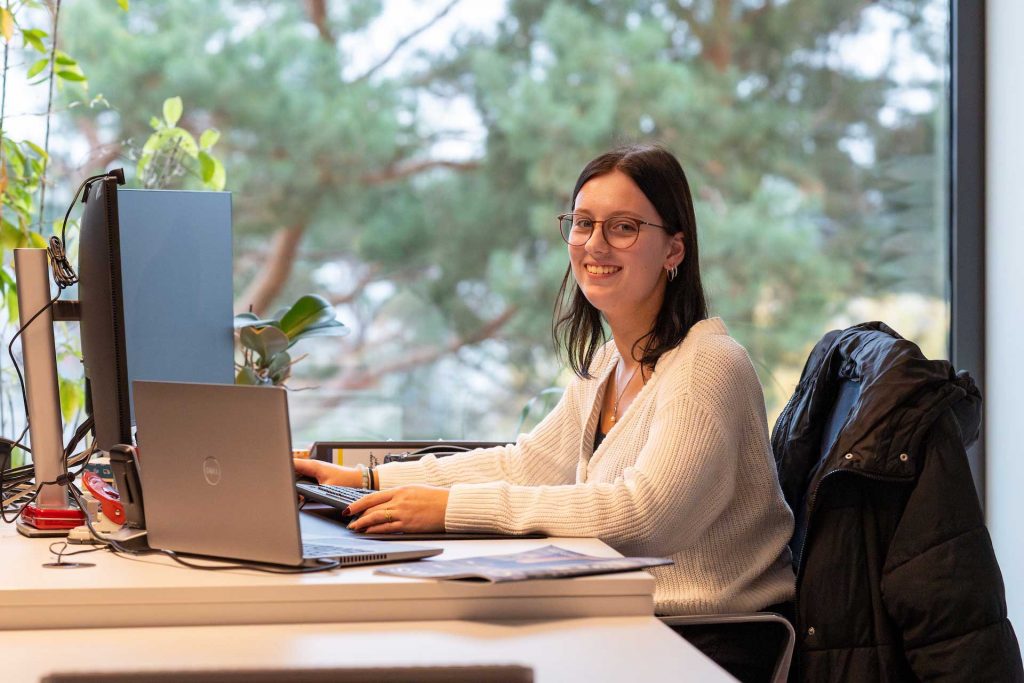 Junge Frau sitzt an einem Tisch in einem Büro vor einem Computer für Kauffrau/-mann für Groß- und Außenhandelsmanagement - ORAFOL Europe GmbH